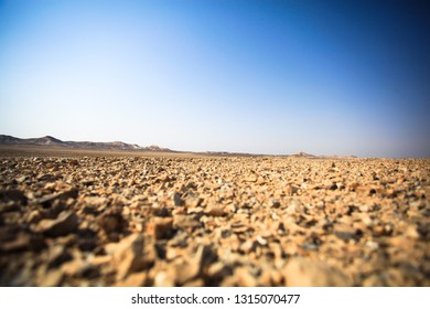View of the desert with hills in the distance. The horizon is overwhelmed and, according to the first plan, misfocusing stones. Without people. Beautiful blue sky