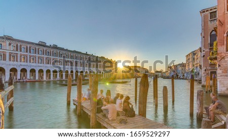 View of the deserted Rialto Market at sunset timelapse, San Polo, Venice, Italy viewed from pier with boats and people across the Grand Canal