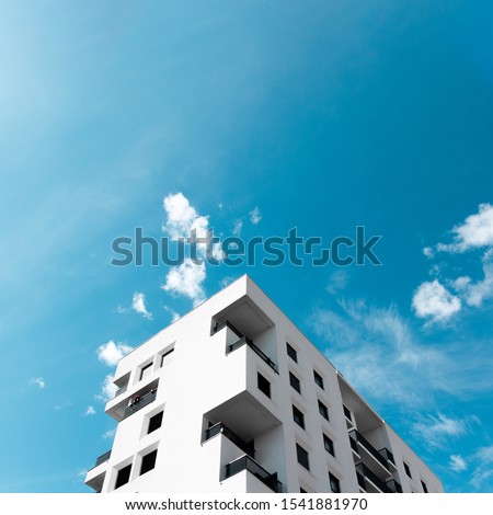 A view at a detail of a modern white apartment building in Lyon, France with blue sky background
