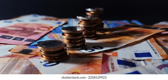 View of different Euro coins stacked in a column on euro banknotes, details on the coin, dark background, photo