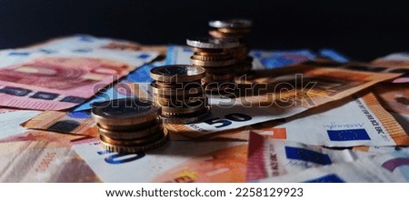 View of different Euro coins stacked in a column on euro banknotes, details on the coin, dark background, photo