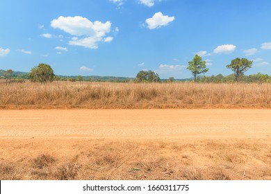 View of dirt road in countryside with blue sky