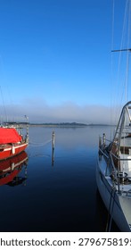 view of a distant ship sailing through morning fog at sea. The vessel appears partially obscured by dense mist, creating a minimalist and atmospheric maritime scene. The composition emphasizes isolation, navigation in low visibility conditions, and the vastness of the ocean environment. Suitable for travel photography, maritime themes, weather concepts, uncertainty, and cinematic storytelling.