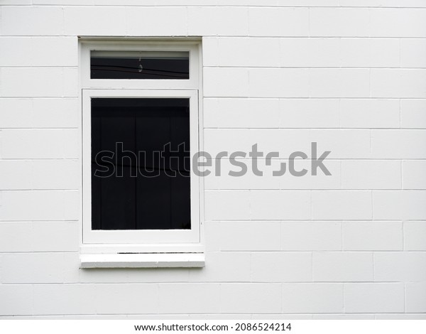 View of divided vertical awning window on white\
brick wall
