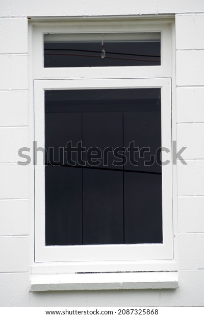 View of divided vertical awning window on white\
brick wall