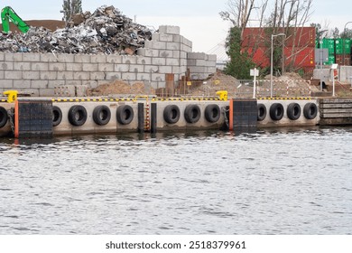 A view of a dock area featuring a pile of scrap metal, concrete blocks, tires, and water. An industrial setting demonstrating environmental impact and construction activities. - Powered by Shutterstock