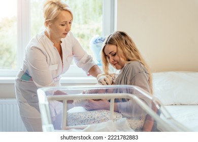 View Of A Doctor Helping A New Mother Feed The Baby With A Breast. Mom Breastfeeding Newborn Baby In Hospital Ward. Breastfeeding Consultant Help Her.