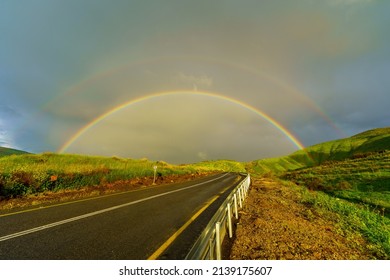 View of a double rainbow, on the slopes of the Golan Heights, with a trilingual mine warning sign, on a foggy winter day. Northern Israel