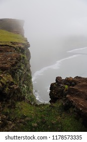 View down from the edge of the cliff on the shore of Atlantic ocean and huge waves on a foggy cold summer day in Iceland, Europe