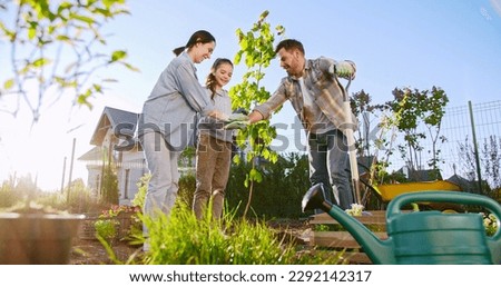 View from down on cheerful Caucasian family finish planting tree in garden and giving high five to each other. Sign and gesture of work done. Father, mother aand teen daughter ending job in orchard.