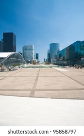View down the open square and center concourse of La Defense and its office buildings from the steps of the Grande Arche in Paris, France on a clear sunny, blue sky day. Vertical copy space - Shutterstock ID 95858797
