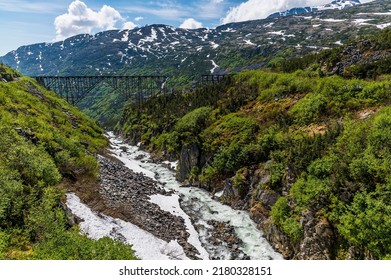 A view down a ravine towards a derelict bridge at the highest point of the White Pass near Skagway, Alaska in summertime