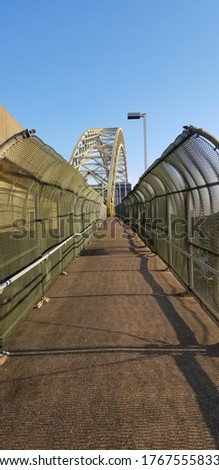 A view down the straight and narrow path of a pedestrian walk way on a bridge in Pittsburgh.