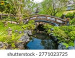 A view down a stream towards a bridge in an ornamental garden in the Imperial City in Hue, Vietnam close to sunset