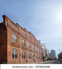 View of downtown Durham NC showing a former tobacco warehouse converted into loft style apartments, with newer buildings in the background