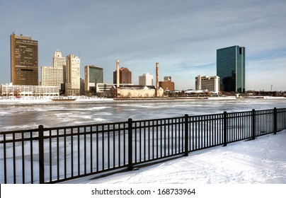 A view of downtown Toledo Ohio's skyline from across the frozen and snow covered Maumee river. A beautiful partly cloudy blue sky makes for a pretty winter scene.