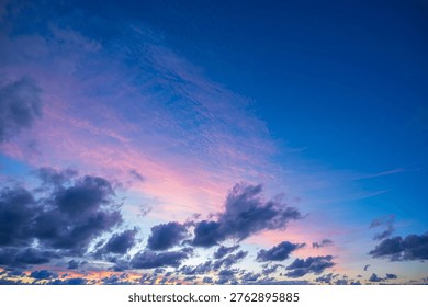 View of dramatic peaceful blue pink sky containing beautiful dark cloud formation during sunset sunrise dawn dusk creating majestic natural atmospheric background with tranquil mood