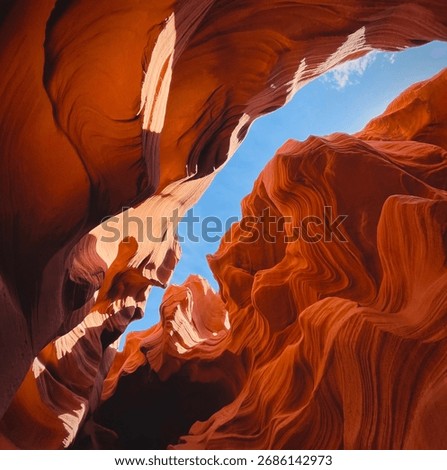 View of the dramatic sandstone formations inside Antelope Canyon, Arizona. Light and shadow enhance the textures of the slot canyon walls under the clear desert sky.