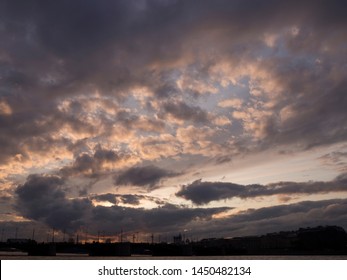 View of the dramatic sky above the sity at sunset with dark blue clouds and pink flashes from the sun's rays 