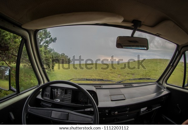 View from the\
driver perspective of a van parked in nature. Concept of a hippie\
escape with a van into\
nature.