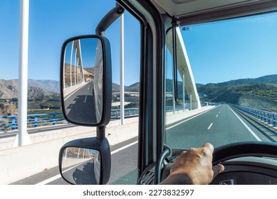 View from the driving position of a truck of the road where it drives when passing over a bridge and of the rear view mirrors.