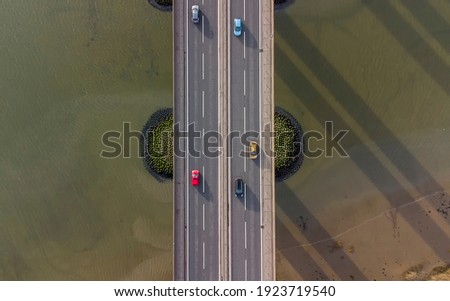 View from a drone looking down on traffic on a road bridge crossing a large river in Suffolk, UK