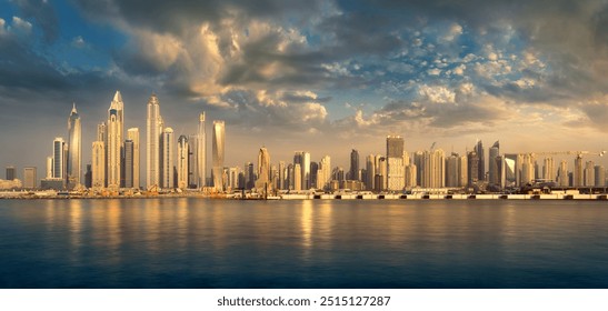 View of the Dubai skyline at sunset from the sea, with the buildings in a row on the horizon reflected in the water. Dramatic clouds and warm sunlit earth colors. - Powered by Shutterstock