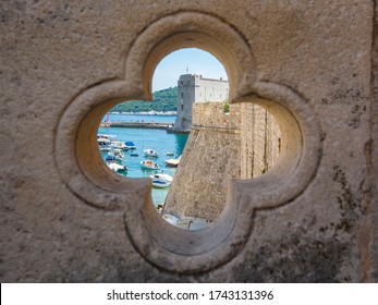 View Of Dubrovnik On Old City, Stone Walls, Sea And Boats With Yachts Through Lucky Clover Trefoil - Ornaments In Gothic Architecture Is Quatrefoil On Bridge At Exit Of Ploce Gate, Dalamtia, Croatia