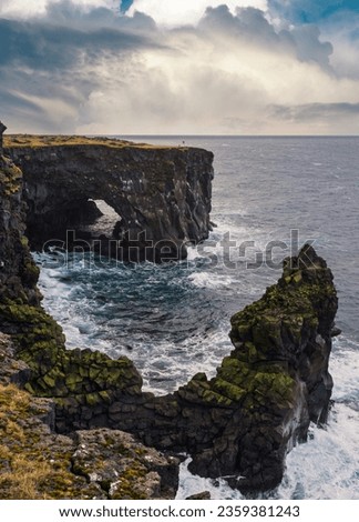 View during auto trip in East Iceland, Snaefellsnes peninsula, View Point near Svortuloft Lighthouse. Spectacular black volcanic rocky ocean coast with cave arch and towers.