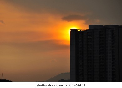 A view at dusk with the sun setting behind tall buildings