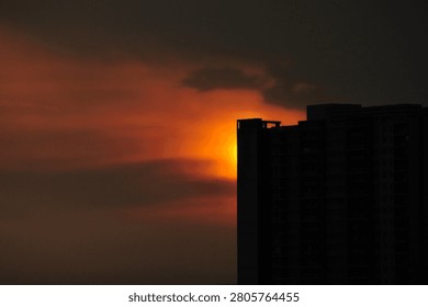 A view at dusk with the sun setting behind tall buildings