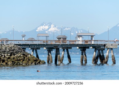 View of Edmonds Pier along Puget Sound in Washington state. The Olympic mountain range can be seen in the background.