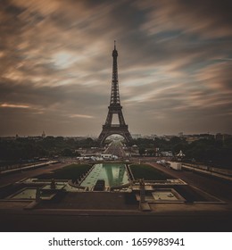 View of the Eiffel tower in Paris on a cloudy day. Famous touristic places and romantic travel destinations in Europe. Travel and tourism concept. Long exposure.