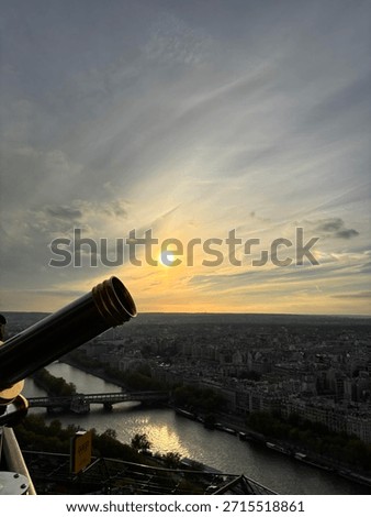 A view from the Eiffel Tower at sunset with a telescope appearing like a canon shooting the sun