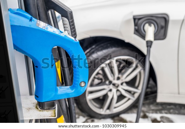 View of an Electric Car Charging and in the\
background a blurred view of a\
car