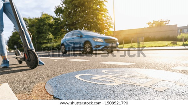 view\
of a electric kick scooter or e-scooter at a Bicycle road sign with\
car passing on a summer day, accident concept\
image