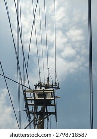 view of an electrical distribution transformer mounted on a utility pole with multiple overhead power lines against a blue sky with clouds. Concept of electricity distribution, energy infrastructure, power transmission, public utilities, and urban electrical network.
