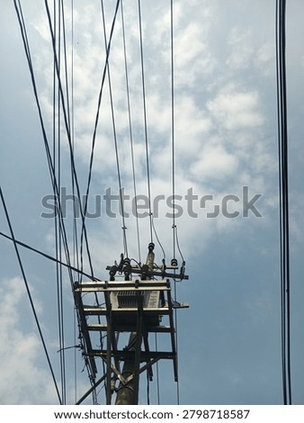 view of an electrical distribution transformer mounted on a utility pole with multiple overhead power lines against a blue sky with clouds. Concept of electricity distribution, energy infrastructure, power transmission, public utilities, and urban electrical network.