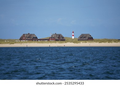 view to the "Ellenbogen" in List east on Sylt, Germany with the big red and white lighthouse on a sunny day - viw from a ship - Powered by Shutterstock