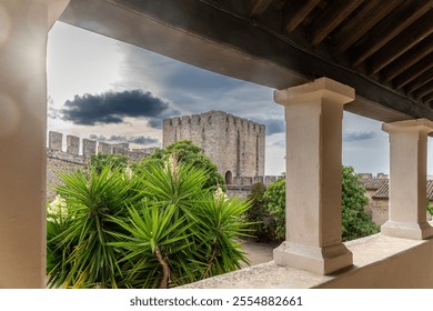 View of Elvas castles historic stone tower surrounded by lush plants, with a covered area framed by columns, enhancing the scene. - Powered by Shutterstock