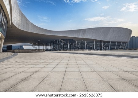 View from empty brick floor towards a modern public building background under blue sky.