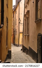 View of an empty, cobble street, alley between city buildings abroad in Stockholm, Gamla Stan. Narrow cobbled stone road in an old small overseas village. Exploring town, enjoying holiday and vacation