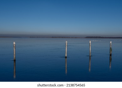 A view of empty docks in the winter. Blue water and a clear blue sky