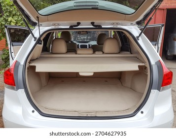 View of the empty open trunk cargo area of a white crossover vehicle with the rear seats and parcel shelf visible