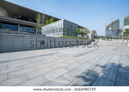 View of an empty road and open ground in front of modern buildings, highlighting contemporary urban architecture and infrastructure.