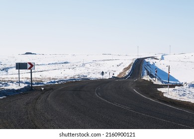 View of an emtpy asphalt road with lanes and snow in winter.
