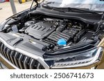 A view of the engine compartment of a modern brown combustion SUV with a large spacious body. Lightly dusty black plastic covers, without manufacturer