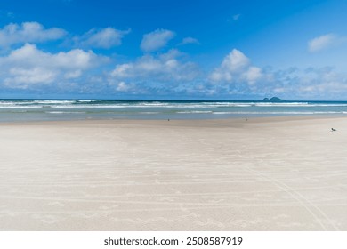 View of Enseada Beach, a beautiful beach with view to the sand, the sea on a blue sky day and few clouds. Guaruja - SP, Brazil. - Powered by Shutterstock