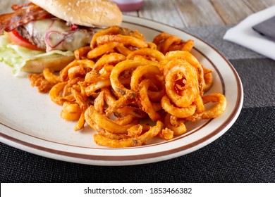 A View Of An Entree Featuring Curly Fries, Next To A Cheeseburger.