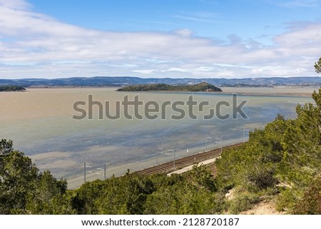 View of the Etang de Bages-Sigean bordered by a railway line from the Sainte-Lucie Regional Nature Reserve in Port-la-Nouvelle (Occitanie, France)